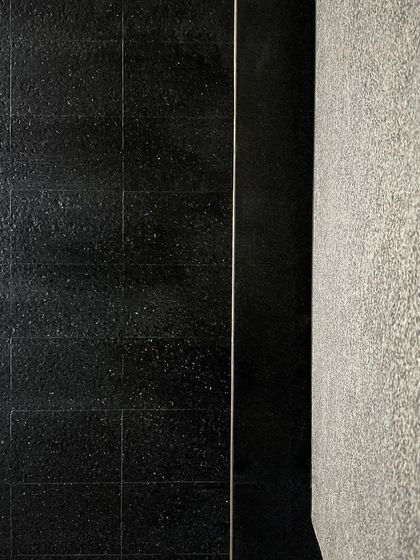 A close-up of material mock-ups at the Courtyard House site, showing the contrast between a polished black stone and a textured grey granite.
