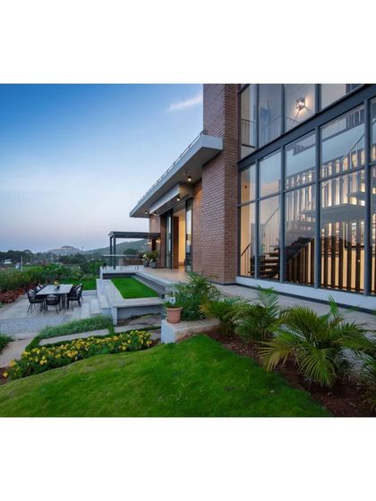 An outdoor patio and terraced garden at the Nandi Hills home. This hardscape design provides a functional space for dining and relaxation, stepping down into a manicured lawn that overlooks the valley, blending architecture with landscape.