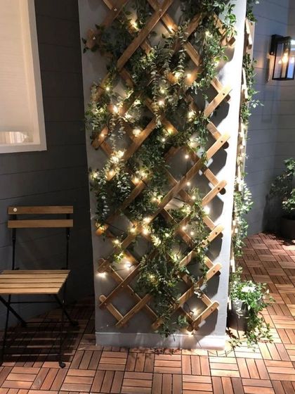 A simple wooden trellis can completely transform a plain pillar or wall. Here, I've used an expandable trellis intertwined with faux ivy and fairy lights to create a charming and whimsical green feature.