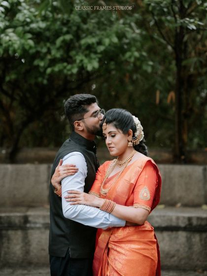 A tender forehead kiss captured outdoors. This classic romantic gesture is a beautiful way to show the couple's affection and bond.