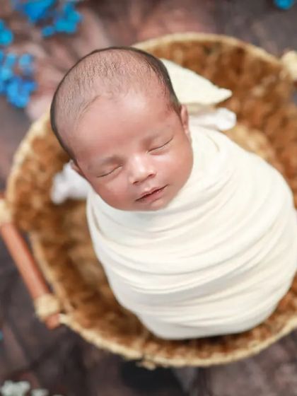 It's a boy! This little man is wrapped snugly in a basket, surrounded by blue and white flowers. A classic and beautiful announcement photo.