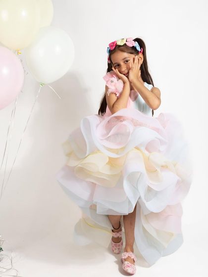 A sweet moment captured in our pastel rainbow gown, surrounded by balloons.