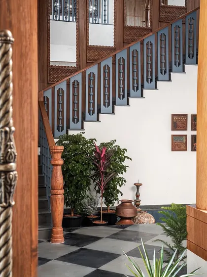 The layout gifted us a grand staircase, which we turned into a visual masterpiece. We used blue balusters to match the main door, contrasted with a rich teak handrail. The adjacent wall is lined with teak and embedded mirrors, creating a truly regal look.