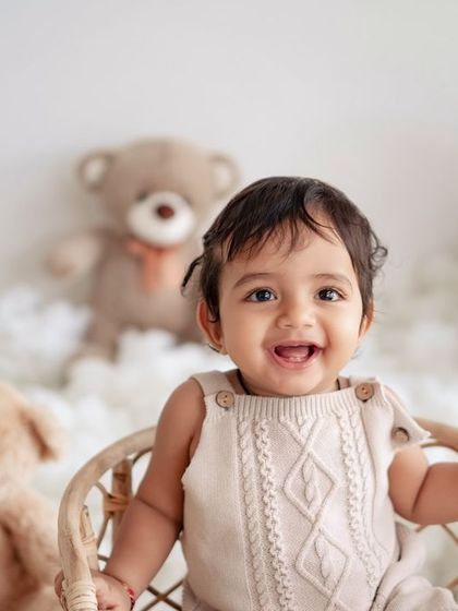 A happy baby boy surrounded by teddy bears in a cloud-like setting.