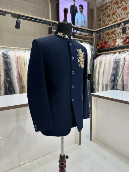 A classic navy blue Jodhpuri suit, elevated with a small, intricate gold embroidered motif on the chest and collar. This is a perfect example of understated elegance.