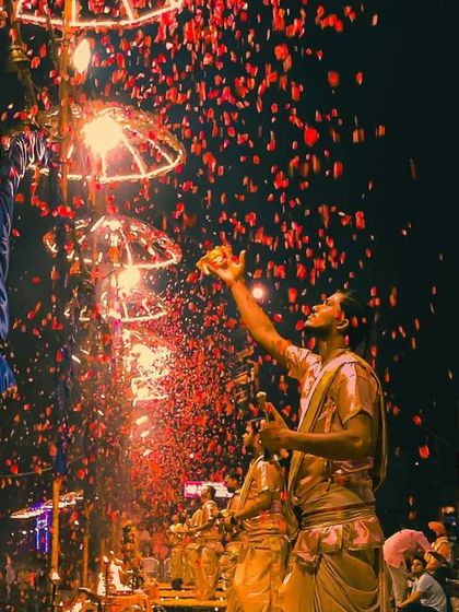 The divine spectacle of the Ganga Aarti during Dev Deepawali. A shower of flowers rains down, capturing the explosive devotion and grandeur of the festival.