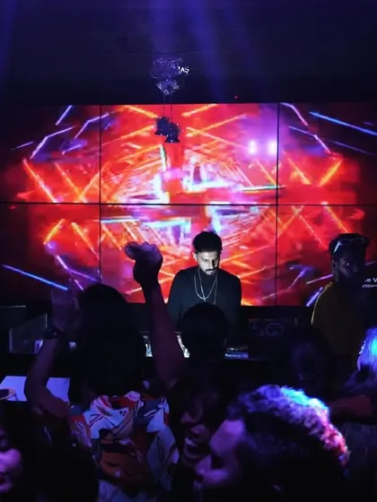 At the heart of my setup is the visual experience. Here I am at the console, surrounded by the crowd, with a massive LED wall displaying custom VJ graphics that sync perfectly with the EDM and bass house tracks.