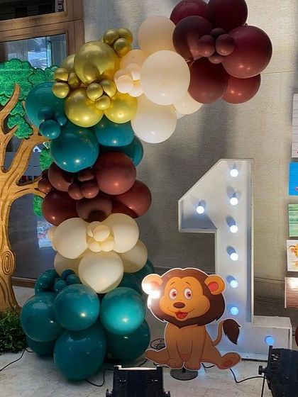 Details of a jungle safari setup, including a large light-up '1' for a first birthday, a custom signpost with fun jungle rules, and a friendly lion cutout.
