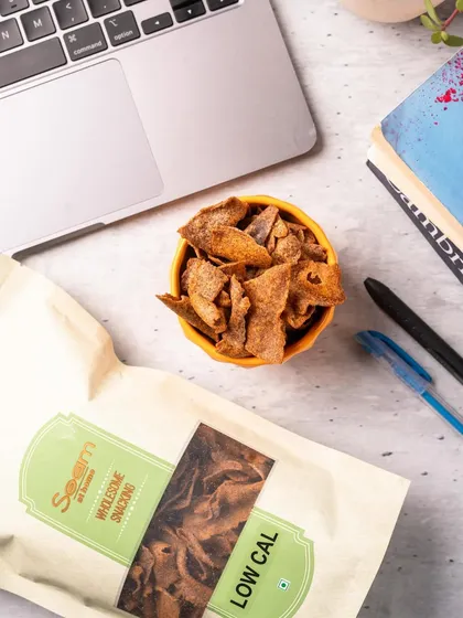 A perfect setup for a study or work break. A bowl of my Nachni Chips sits beside a laptop and books, ready to provide some well-deserved, wholesome fuel.