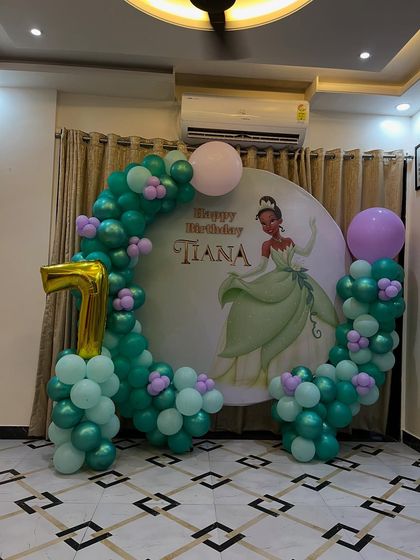 A closer look at the Princess Tiana first birthday setup, highlighting the balloon colors and the custom printed backdrop.