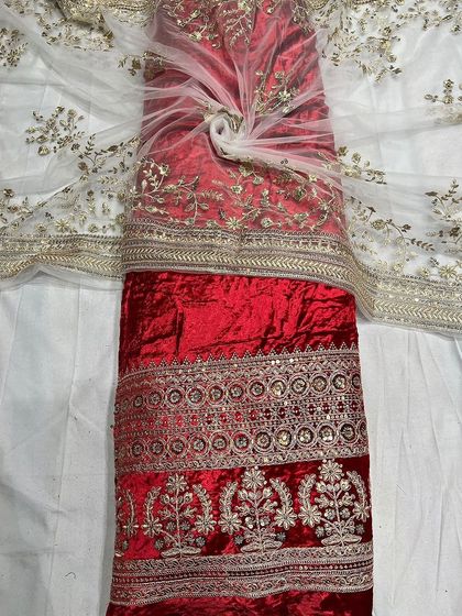 A vibrant red velvet textile, ideal for bridal wear or festive occasions. The fabric is shown with its matching embroidered net, showcasing a complete set for a lehenga or anarkali.