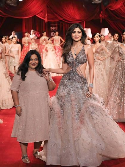 Shilpa Shetty posing with the designer against a backdrop of models. This finale shot captures the entire collection and the success of the show.