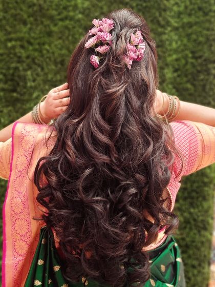 A beautiful shot of the hairstyle for this engagement look. The long, flowing curls are decorated with delicate pink flowers for a romantic feel.