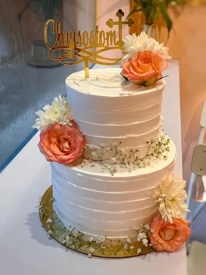 A beautiful two-tier Communion cake for Chrysostom. The simple ridged buttercream texture is elevated with delicate arrangements of fresh peach roses, white chrysanthemums, and baby's breath.