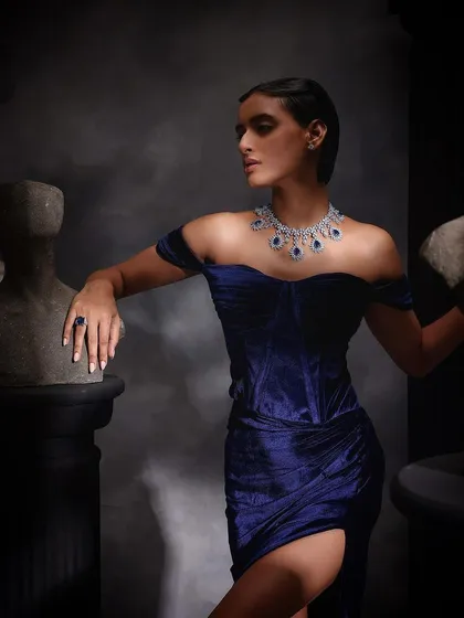 A wide shot for Purab Paschim, placing the model and her sapphire jewelry among classical-style statues for a timeless, artistic feel.