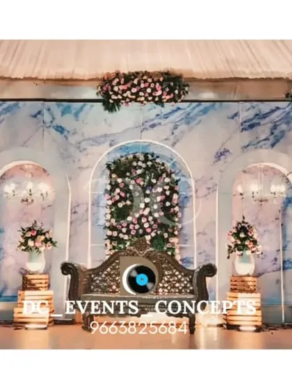 A beautiful wedding reception setup featuring a blue marble-patterned backdrop and clean white arches. The design is accented with delicate floral arrangements, creating a serene and elegant atmosphere.