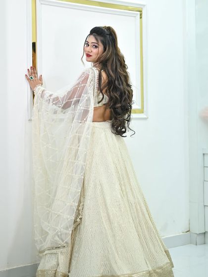 A back three-quarter view of the ivory chikankari lehenga, highlighting the sheer dupatta and the backless blouse.