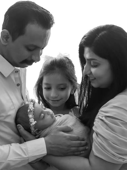 A precious black and white photo including the older sister, who looks so proud and gentle with her new baby sibling.