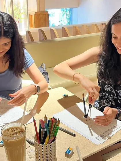 Two participants focused on getting their mandala grids just right. It's wonderful to see people enjoy the process of learning and creating together at a cafe workshop.