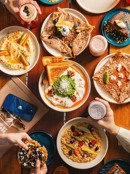 Our lifestyle photography places food and beverages in a relatable, aspirational context. This flat lay of a cafe's brunch spread, complete with hands interacting with the food, creates an authentic scene that resonates with social media audiences.