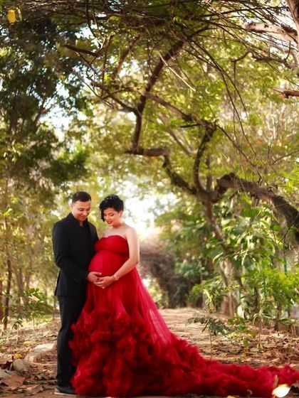 A classic portrait in the woods. This vibrant red strapless gown with a ruffled train creates a beautiful contrast with the green foliage, making the mom-to-be the star of the show.
