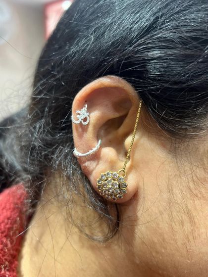 A spiritual stack in mixed metals, featuring a silver Om and crescent stud with a gold chain and lobe earring.