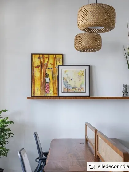 A detail shot from the 'Sepalika' office, showing the art shelf with wicker pendant lights hanging above. The mix of art and natural textures is key to the space's warm aesthetic.