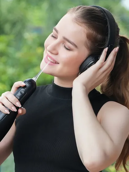 A model enjoys a moment of relaxation while using the water flosser. This image effectively communicates ease of use and satisfaction, key selling points for any gadget.
