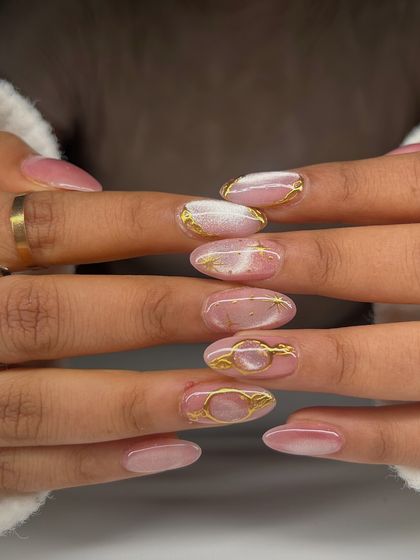 A full view of the pink cat-eye and gold accent nails. The abstract gold shapes add an artistic and glamorous touch.