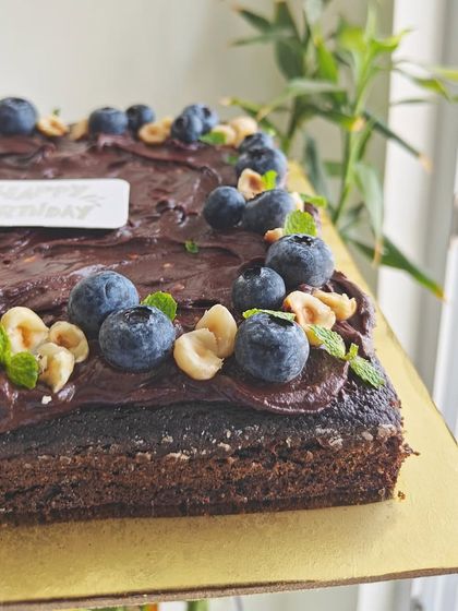 A close-up showing the texture of the sugar-free dark chocolate ganache, topped with crunchy hazelnuts and fresh blueberries.