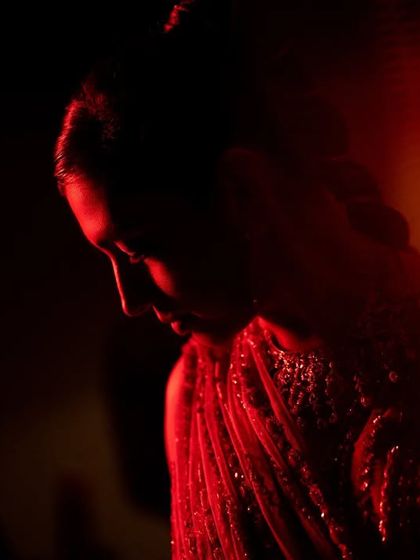 Using creative lighting to create a dramatic and artistic bridal portrait. The deep red light adds a moody and romantic feel, highlighting the bride's silhouette in a unique way.