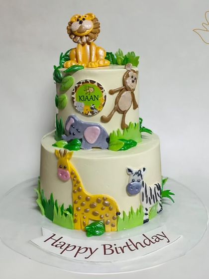 A two-tier jungle cake for Kiaan's birthday. This design features a lion on top and a giraffe, elephant, and zebra around the sides for a fun safari adventure.