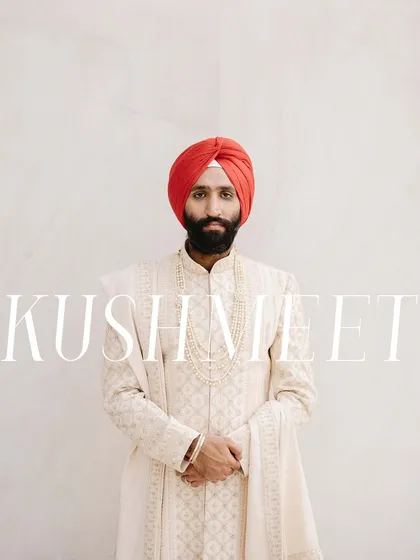 A classic, minimalist portrait of the groom, Kushmeet. The clean white background and his direct gaze create a strong and modern image, highlighting his sharp red turban.
