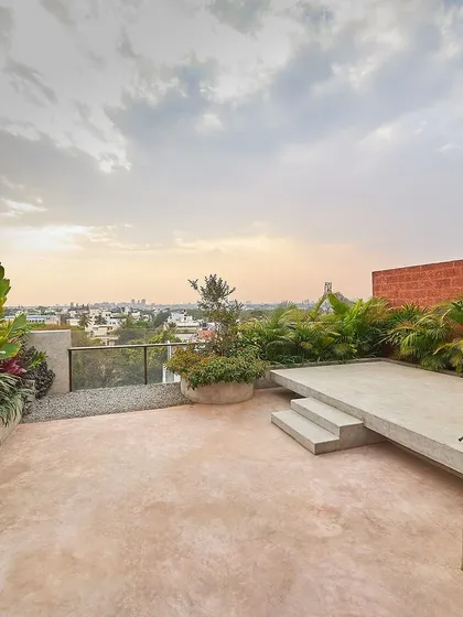 This rooftop terrace for the Magnolia Residence transforms an urban penthouse into a private oasis. We used a mix of lush tropical plants, pigmented cement flooring, and a raised platform to create a multi-level garden with views of the Bangalore city skyline.