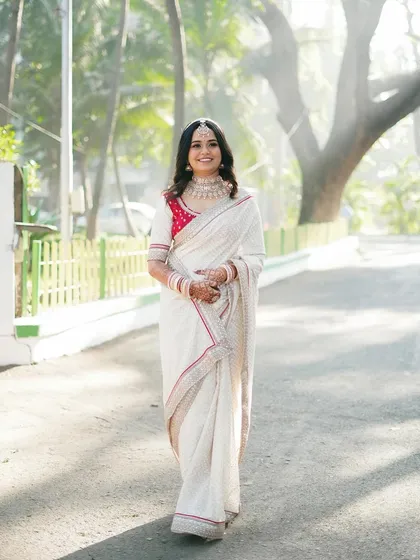 A classic portrait of the bride, smiling warmly. Her simple yet elegant white saree makes for a timeless and sophisticated bridal look.