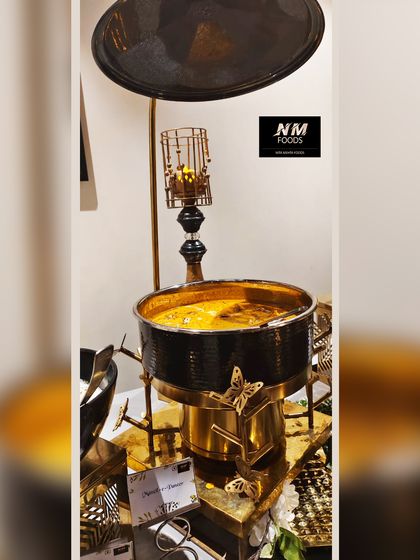 A close-up of one of our ornate chafing dishes. The combination of the black pot with gold butterfly accents creates a look of modern luxury that elevates any buffet line.