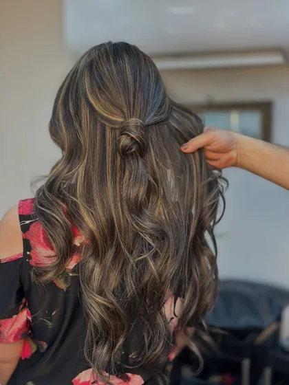 A close up of our stylist putting the finishing touches on this wavy balayage look. It's all about creating those perfect, touchable waves.