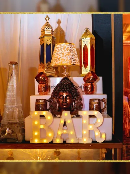 Our bar decor is designed to be a conversation starter. This setup features a mix of Moroccan lanterns, a Buddha head statue, and our signature "BAR" marquee lights for an eclectic look.