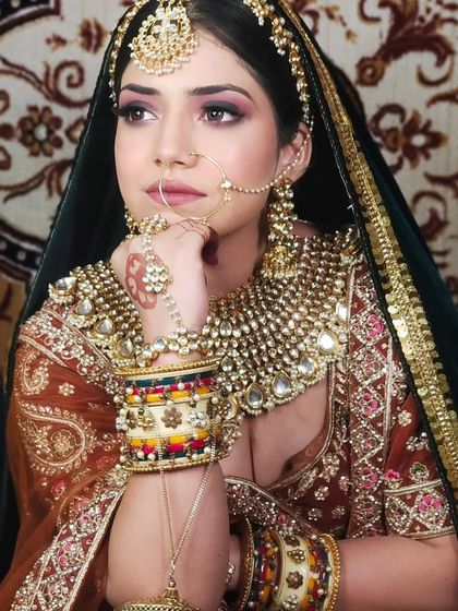 A bride wearing a heavy Kundan set with intricate bangles. The dark green dupatta provides a beautiful contrast to the golden jewellery.