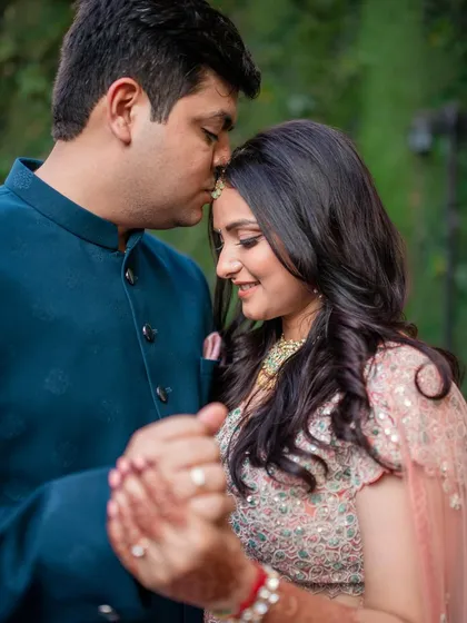 An intimate moment as the groom-to-be kisses his fiancée's forehead.