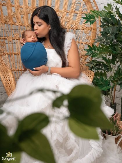 A tender kiss for her newborn. This close-up shot, with a soft foreground element, creates an intimate and artistic portrait of a mother's love.