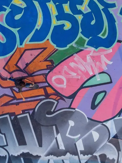 An overhead shot capturing a skater moving across a complex collage of different graffiti styles, showing the diversity of the artists involved.