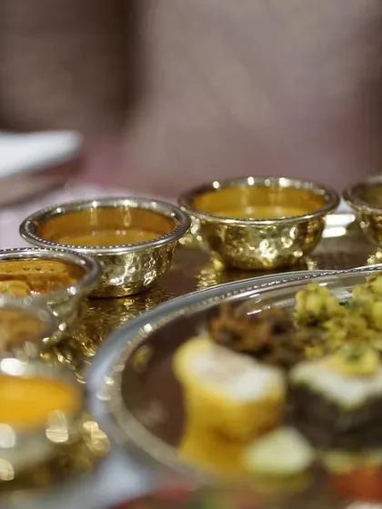 A close-up of a traditional Indian meal served in hammered golden bowls, showcasing the rich colors and textures of the different curries and dals.