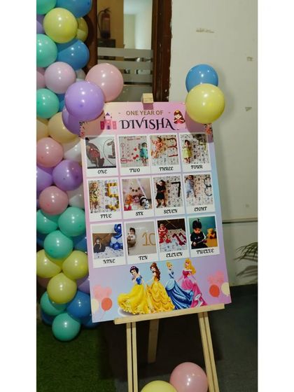 This milestone board showcases 'One Year of Divisha' with a photo from each month. It's a heartwarming detail that tells the story of the baby's first year for all the guests to see.
