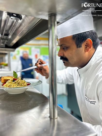 In the heart of our kitchen, a chef carefully plates a pasta dish, ensuring every element is perfectly placed before it reaches the guest.
