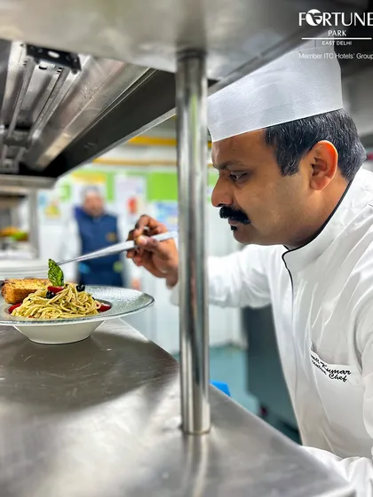 In the heart of our kitchen, a chef carefully plates a pasta dish, ensuring every element is perfectly placed before it reaches the guest.