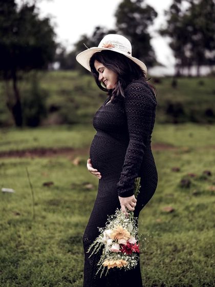 A beautiful solo portrait of the mom-to-be in a field, wearing a hat and holding a bouquet. Her gentle smile and the soft light are perfect.