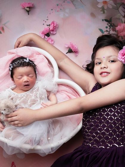 These little hearts together create so much love. A creative portrait combining a posed newborn with her proud and beautiful big sister.