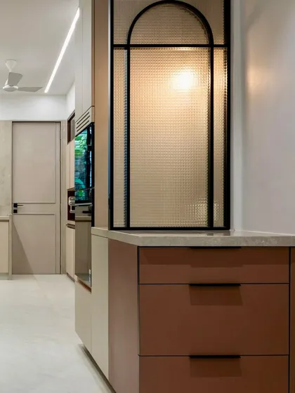A wider view of the appliance nook, showing how it sits between the kitchen and the adjacent nap room. The textured glass divider provides separation while still allowing light to pass through, connecting the two spaces.