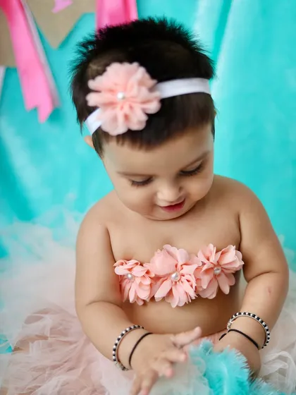 A quiet, candid moment as this baby girl looks down, playing with the soft textures of her tutu.